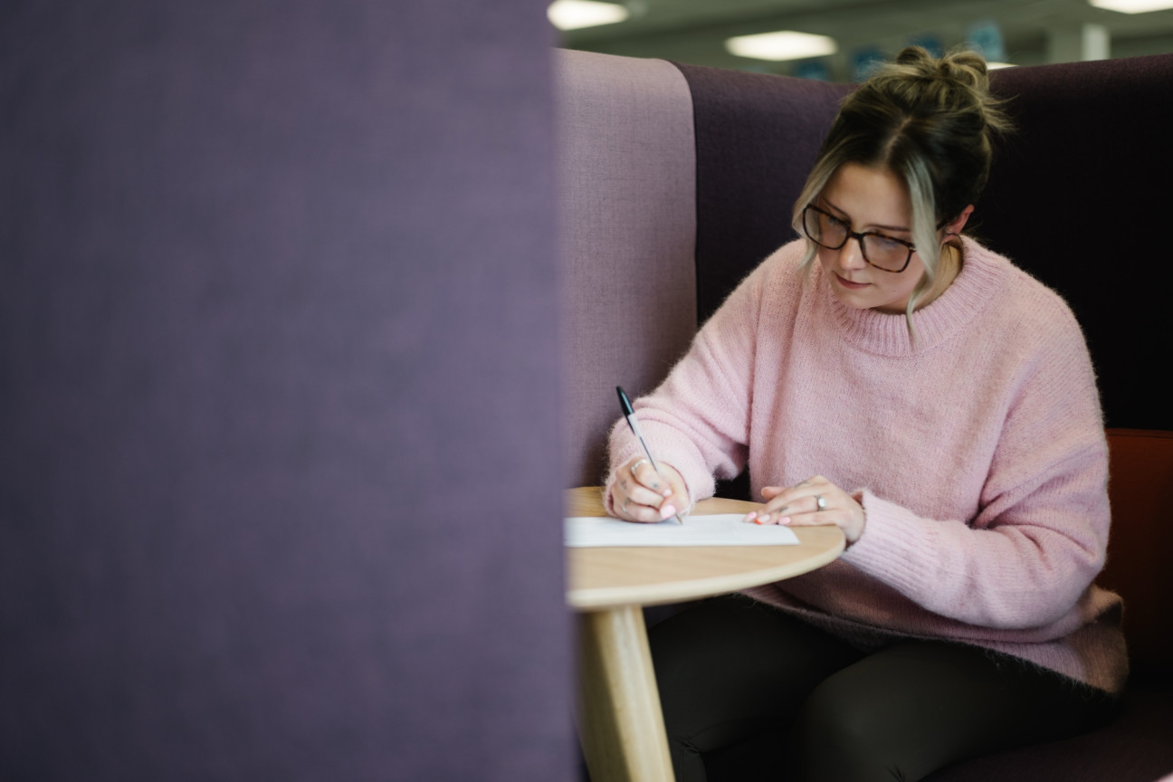 Colleague in quiet working space writing with a pen and paper