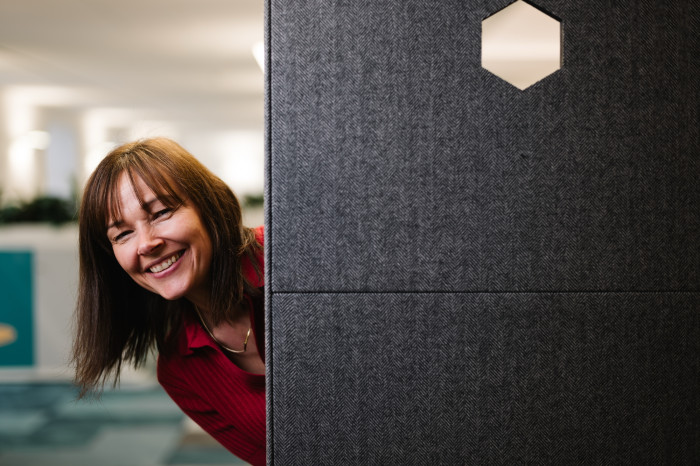 Colleague peering and smiling from behind breakout space seating.