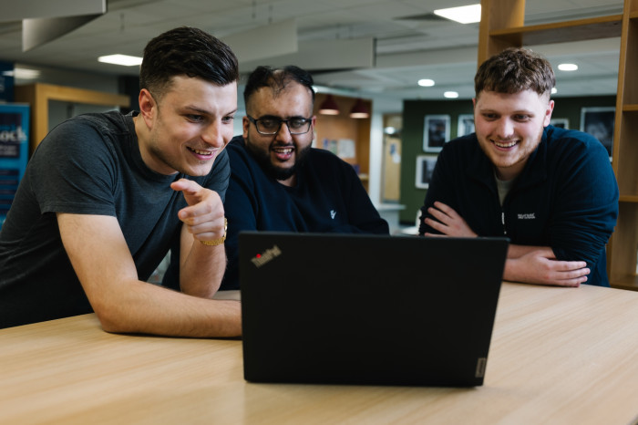 Three colleagues together at computer desk at Skipton Head Office.