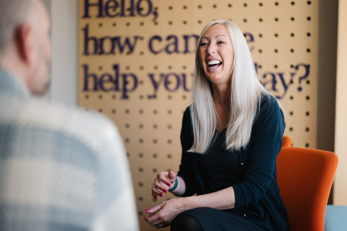 Colleague laughing with customer in Skipton branch seating area.