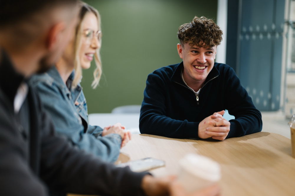 Colleague smiling in team meeting at Skipton Head Office.