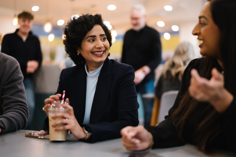 Colleague smiling with coffee drink in meetng.