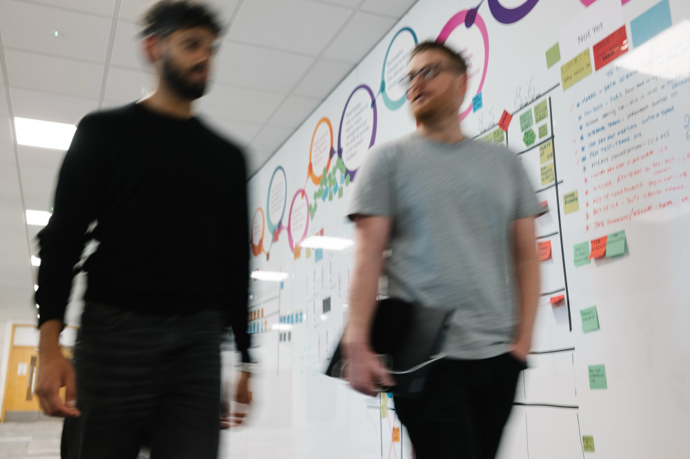 Two colleagues walking down corridor together at Skipton Head Office.