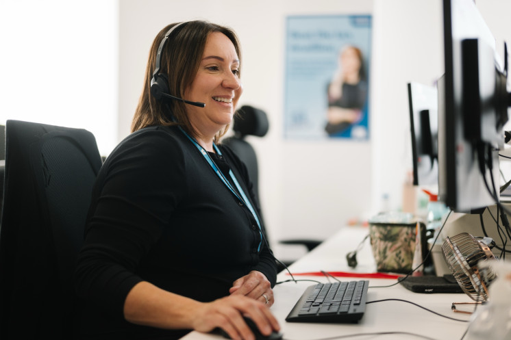 Colleague wearing headset whilst working at computer desktop.