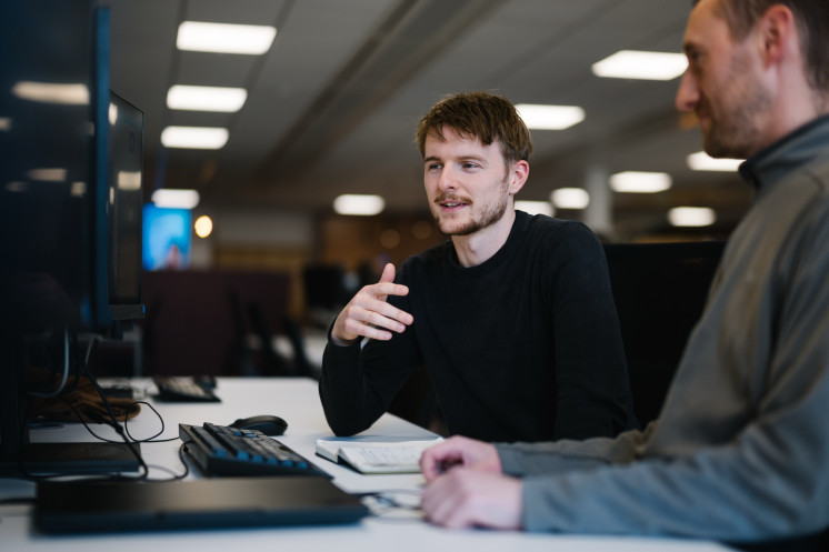 Colleagues working together at computer desktop.