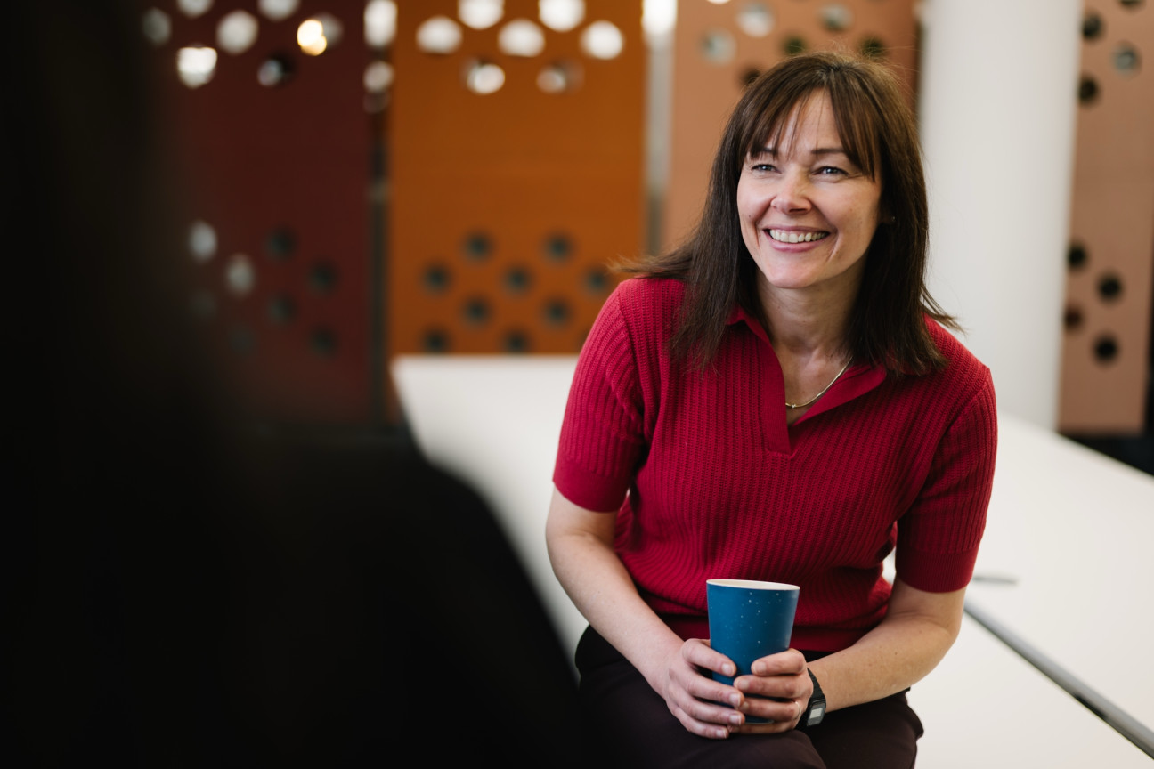 Sarah holding coffee cup and chatting at Skipton Head Office.