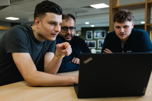 Three colleagues working at laptop together.
